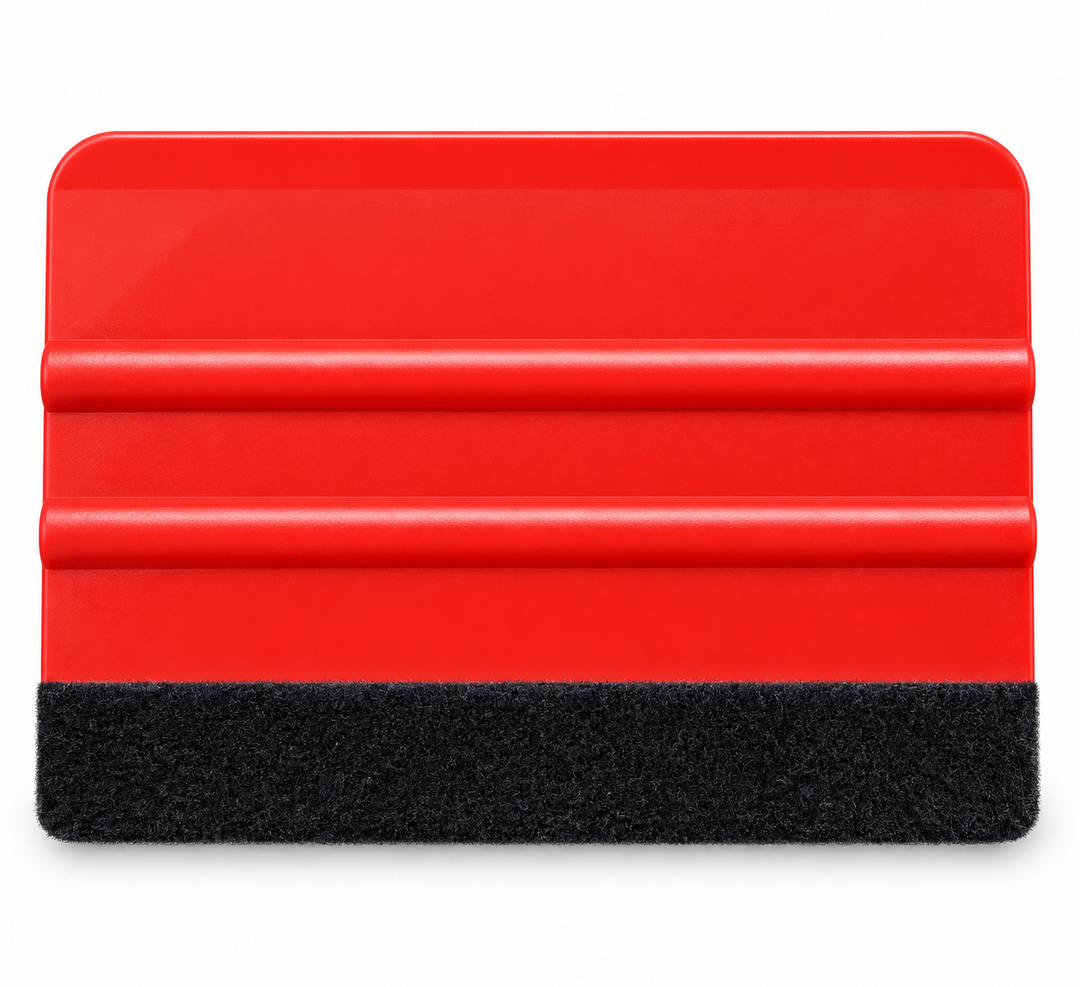 A red plastic squeegee with a black textured felt along the xa edge, shown on a plain white background.